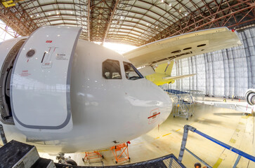 Cockpit outside and nose of an airplane with an open door, jet airliner being maintained in an...