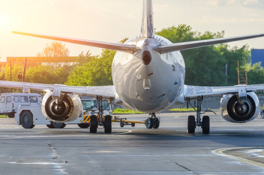 Airplane execute push back operation at airport. Aircraft service for flights before departure in the evening at sunrise