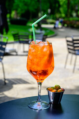Waiter prepared the Aperol Sprits summer cocktail with Aperol, prosecco, ice cubes and orange in wine glass, ready to drink on sunny terrace