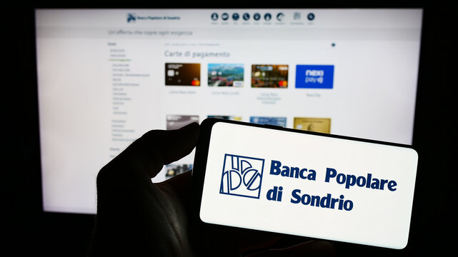 Stuttgart, Germany - 08-30-2023: Person holding smartphone with logo of Banca Popolare di Sondrio S.C.p.A. (BPSO) on screen in front of website. Focus on phone display.