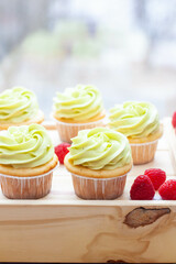 Preparation of pistachio cupcakes with fresh raspberry. Rustic wooden background, close up