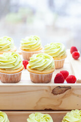 Preparation of pistachio cupcakes with fresh raspberry. Rustic wooden background, close up