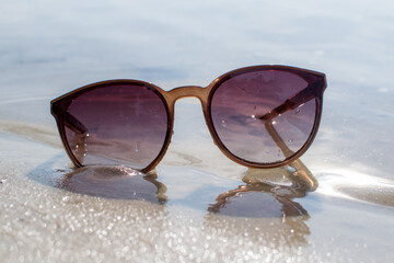 Sunglasses in the sand on the beach, sunny beach, outdoor recreation.