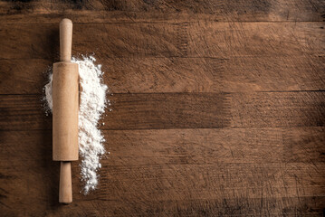 Rolling pin and flour on wooden board
