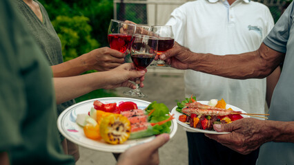 Home Garden BBQ Party, Wine Glasses Clink in Family Toast, enjoying harvest time together outside at front of house, grandfather and grandfather asian people, man and woman