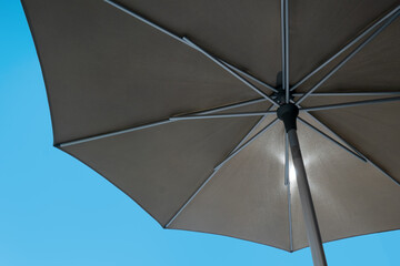 detail of brown umbrella with clear blue sky in background