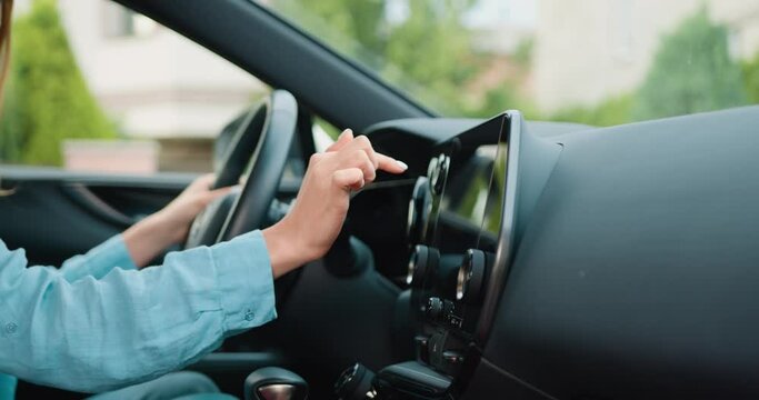 Side view of caucasian woman hand which typing needed coordinates on navigator touchscreen with modern assistance functions. Girl making scrolling and typing text on touch screen monitor on car.