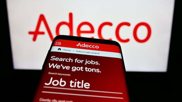Stuttgart, Germany - 09-02-2023: Smartphone with website of recruiting company Adecco on screen in front of business logo. Focus on top-left of phone display.