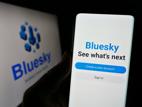 Stuttgart, Germany - 09-02-2023: Person holding smartphone with webpage of social network initiative Bluesky on screen in front of logo. Focus on center of phone display.