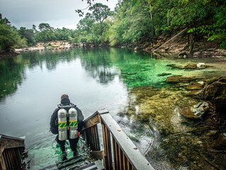 Diver in doubles entering the greenish spring waters of Troy Springs State Park, Florida
