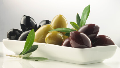 olivenmix drei sorten, schwarze oliven, grüne oliven, auberginefarbige oliven, olivenblätter, weisse schale