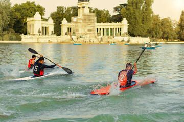 Three men racing kayaks on the lake at Retiro Park in Madrid, Spain