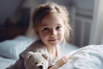 a toddler, a child girl, at home in the children's room sitting on her cot, with a cuddly toy, a teddy bear, joyful grin or smile, good mood on a new morning 