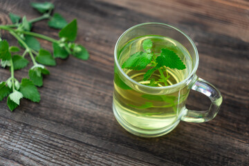 clear glass tea cup on table with green leaves background with soft sunlight in the morning, giving...