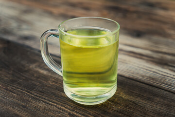 tea in glass mug on wooden table, healthy hot drink and home remedy for coughs, sore throat, digestive problems, gingivitis and sweating, dark green background, copy space, selected focus