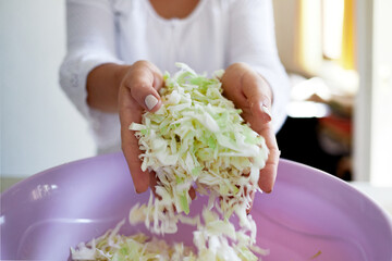 Woman's hands hold shredded cabbage. Dietary vitamin salad. Close-up. Selective focus.