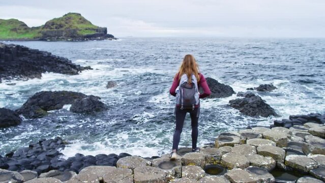 Woman walking towards shoreline at giant's causeway Ireland