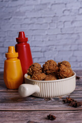 fried chicken with ketchup and mustard in a yellow terracotta bow with star anise on an old wooden table