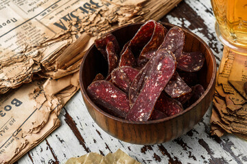 Jerky, Sujuk, Basturma, dried cured smoked sausage in bowl in wooden background, snacks for beer