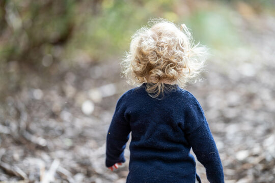blonde todder walking in a forest on a hike in spring