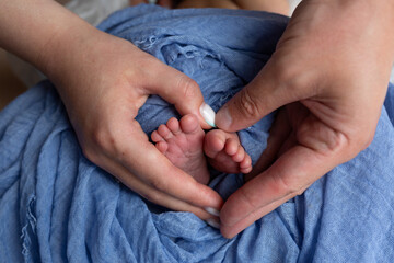 feet of a newborn baby in the hands of parents. legs on a blue background. baby feet