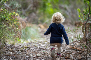 blonde todder walking in a forest on a hike in spring