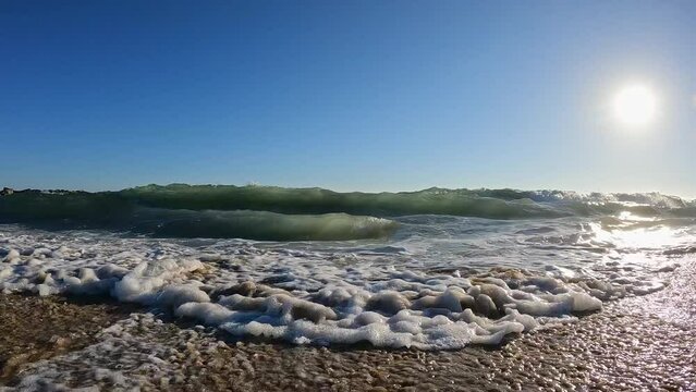 Slow motion of waves crashing into camera on the beach in sunny California.