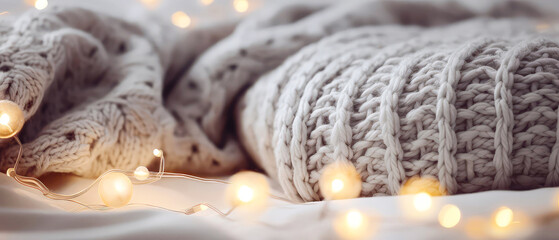 Close up of cozy grey,  knitted merino blanket with garland, bokeh. soft, warm background. Knitted texture. Fall evening concept. generative ai