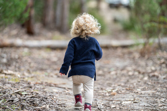 blonde todder walking in a forest on a hike in spring