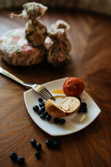 Soft cheese balls adorned with blueberries and paprika, artfully arranged on a white plate atop a rustic wooden table. Delightful culinary composition.