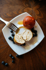 Soft cheese balls adorned with blueberries and paprika, artfully arranged on a white plate atop a rustic wooden table. Delightful culinary composition.