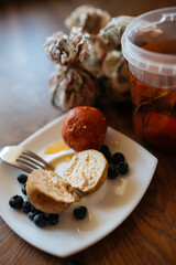 Soft cheese balls adorned with blueberries and paprika, artfully arranged on a white plate atop a rustic wooden table. Delightful culinary composition.