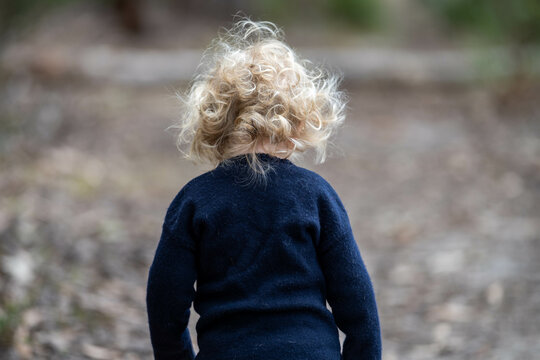 blonde todder walking in a forest on a hike in spring