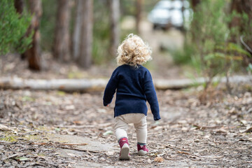 blonde todder walking in a forest on a hike in spring