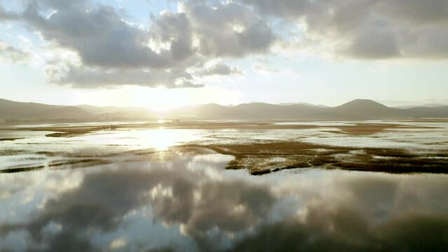 Push In Shot Of Lake Cerknica, Largest intermittent lake in Europe At Epic Morning Sunrise With Symmetric Reflection In The Water, Surrounded With Wet Meadows, Hills, Morning Sky With Clouds.