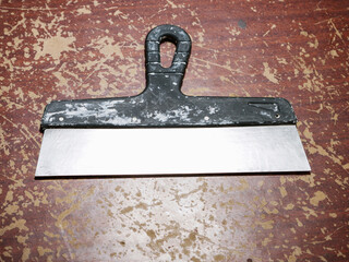 Old and used plastering spatula with dirt and mortar on a brown old rough wooden surface. House...