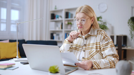 Senior woman interior designer working on a project from home office, choosing colors and materials