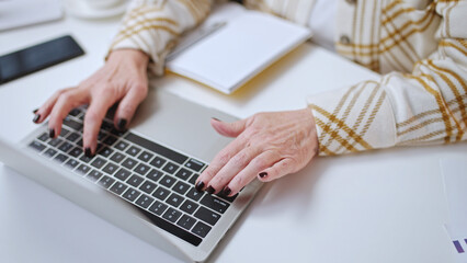 Close-up of a woman typing on laptop keyboard, distance work, web surfing, online shopping