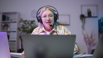 Senior woman gamer commenting video game, taking part in an online tournament from home office