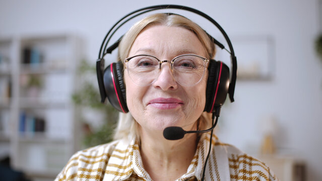 Portrait of a smiling senior woman with a headset answering phone calls, tech support
