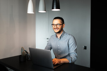 Portrait of handsome young happiness man, working home at laptop. Wearing eyeglasses and t-shirt....