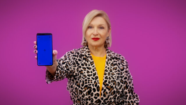 A senior woman is showing a smartphone with a pre-keyed screen ready for your advertisement
