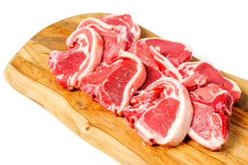 Stack of fresh lamb loin chops on wooden cutting board and on white surface. Premium high quality red meat. Butcher craft. Uncooked product.