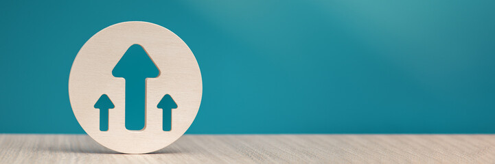 Arrow pointing up on a blue background. Banner with an arrow in a wooden circle close-up pointing up with copy space.