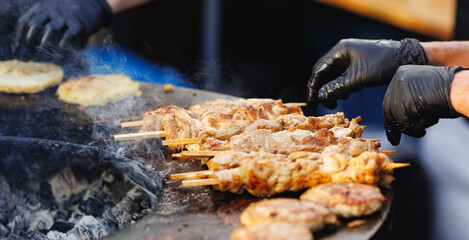 Cook grills chicken kebab steaks open fire. Concept Summer Street food festival