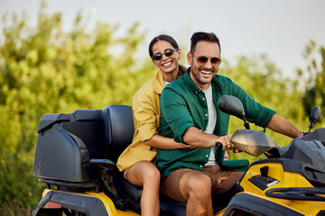 Portrait of a smiling love couple having a quad bike ride in nature.