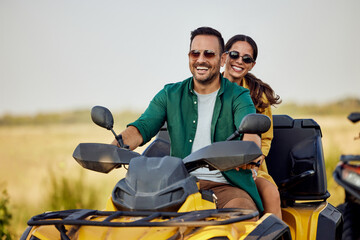 Portrait of a happy love couple having an adventure on a quad bike in nature.