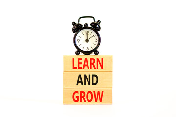 Learn and grow symbol. Concept word Learn And Grow on beautiful wooden block. Black alarm clock. Beautiful white table white background. Business, education learn and grow concept. Copy space.