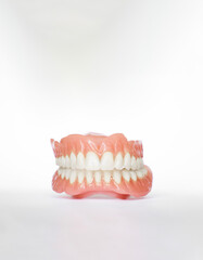 Vertical shot of dentures over white background with copy space. Dental plan. Dentistry prosthesis. Dental Health