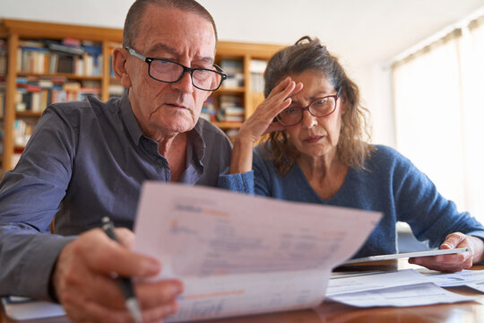 Senior male and senior female  with tablet and calculator upset while managing bills and taxes. Couple doing small business accounting